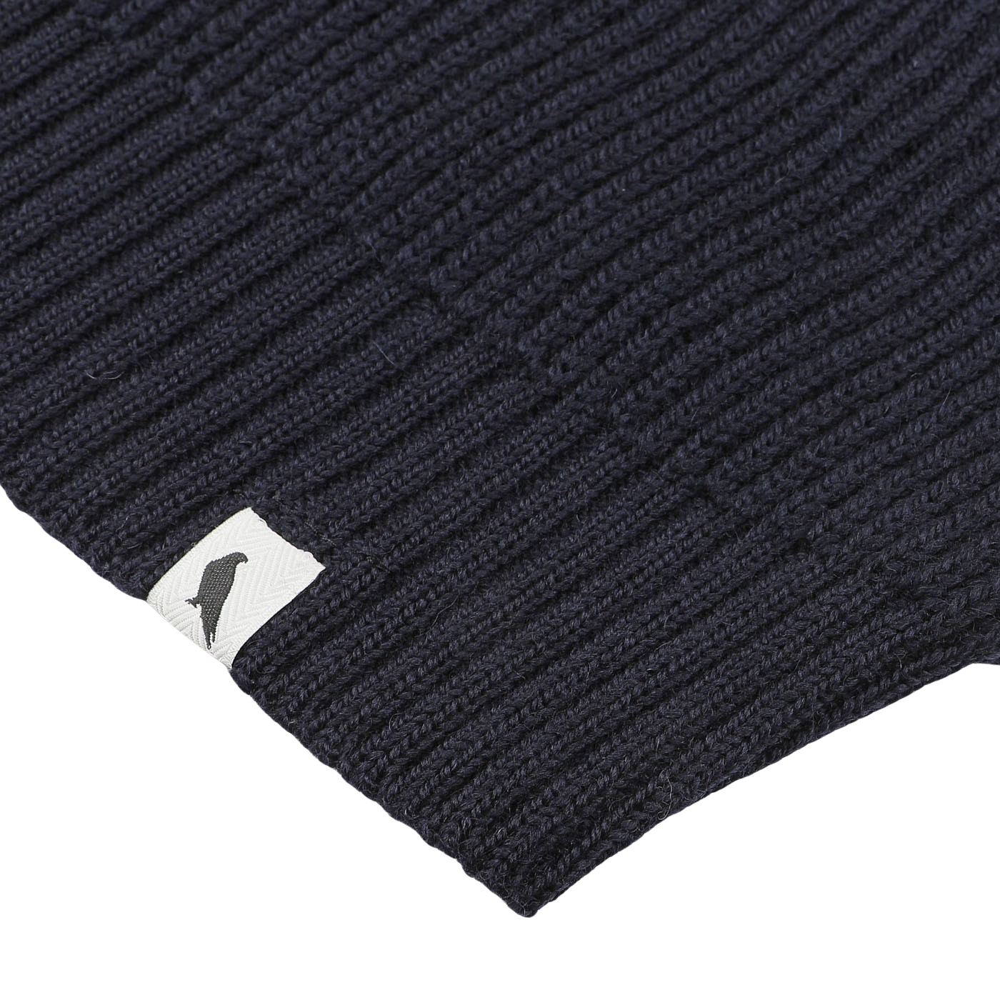 Close-up of the Navy Blue Wool Ford Raglan Crewneck from Peregrine, a premium British knitwear piece featuring a ribbed knit fabric and a small white tag with a black bird silhouette.