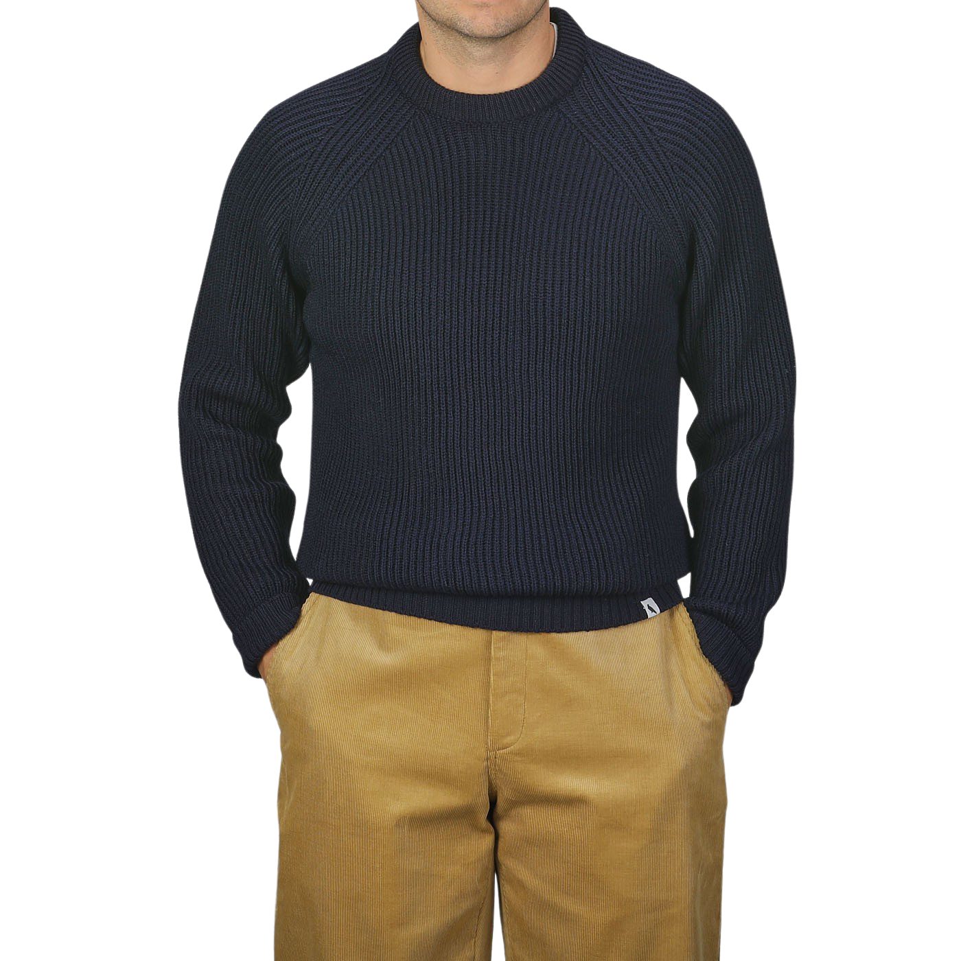 A person wearing a Peregrine Navy Blue Wool Ford Raglan Crewneck sweater and tan pants stands against a neutral background with their hands in their pockets.