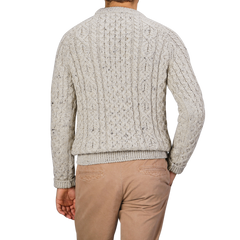 A person wearing a Peregrine Skiddaw Beige Merino Wool Hudson Aran Jumper and tan pants, viewed from the back against a plain gray background.