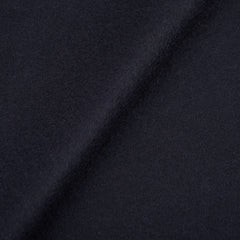 Close-up of a dark navy cashmere fabric with fringed endings, highlighting a diagonal seam. The texture appears soft and slightly fuzzy, embodying the luxurious feel of the Piacenza Cashmere Aeternum Scarf.