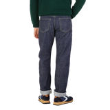 Rear view of a person wearing Resolute's Dark Blue Cotton 714 One Wash Jeans and multicolored sneakers, with a green sweater tucked in.