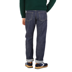 Rear view of a person wearing Resolute's Dark Blue Cotton 714 One Wash Jeans and multicolored sneakers, with a green sweater tucked in.