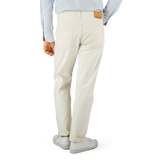 Man standing in a profile view wearing off-white Resolute Cream Cotton Selvedge 714 One Wash Jeans with a tucked-in light blue shirt and white sneakers.