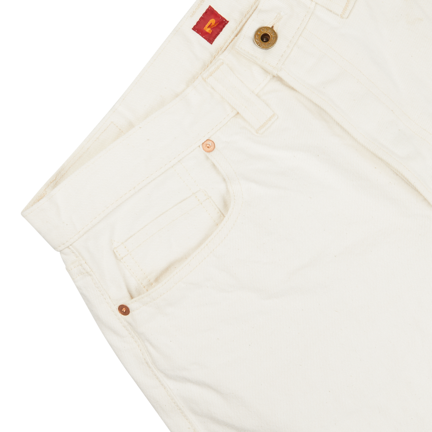 Close-up of a Resolute Cream Cotton Selvedge 714 One Wash Jeans pant featuring copper buttons and tan stitching, with a focus on the front pocket and waistband.