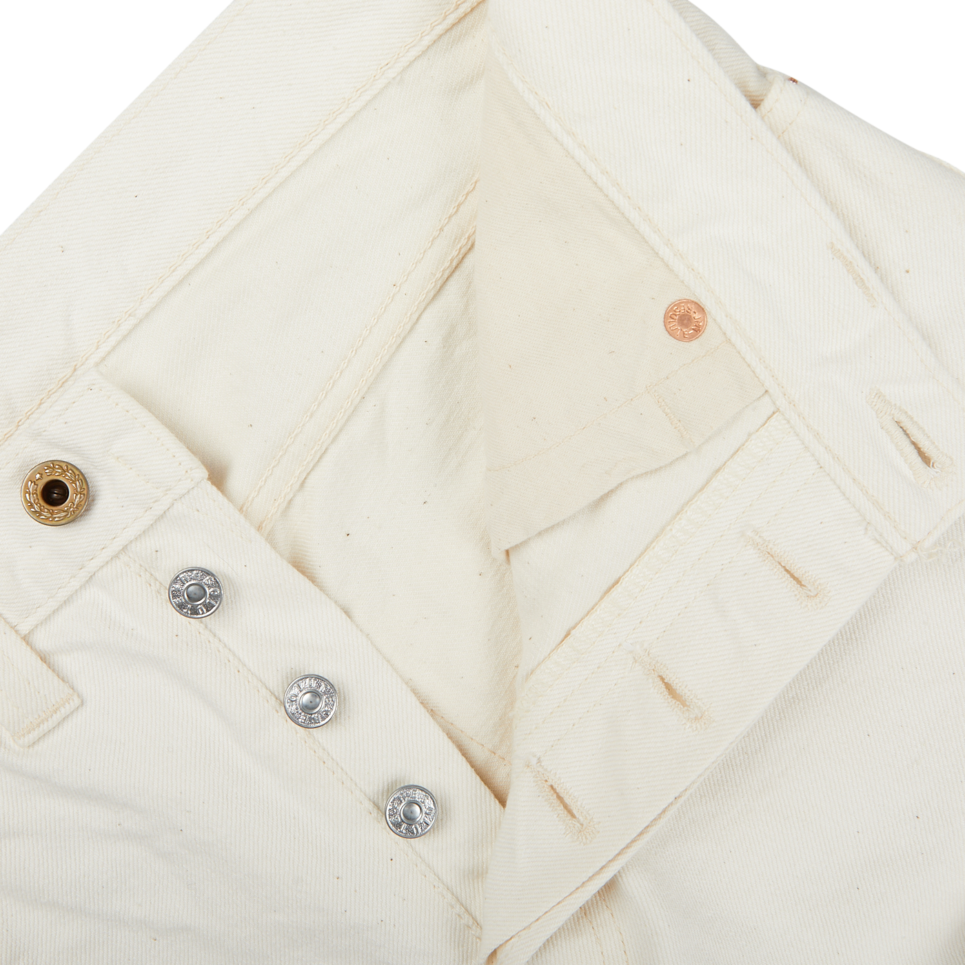 Close-up of a white denim jacket with mixed metal buttons, showcasing details of the collar and button placket, paired with Resolute Cream Cotton Selvedge 714 One Wash Jeans.