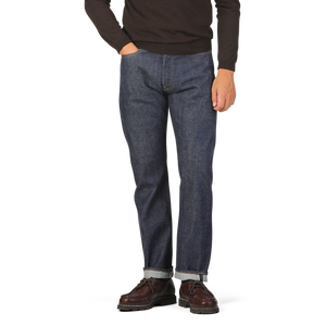 Person wearing a brown sweater with Dark Blue Cotton 710 One Wash Jeans by Resolute and brown shoes, standing against a plain background.