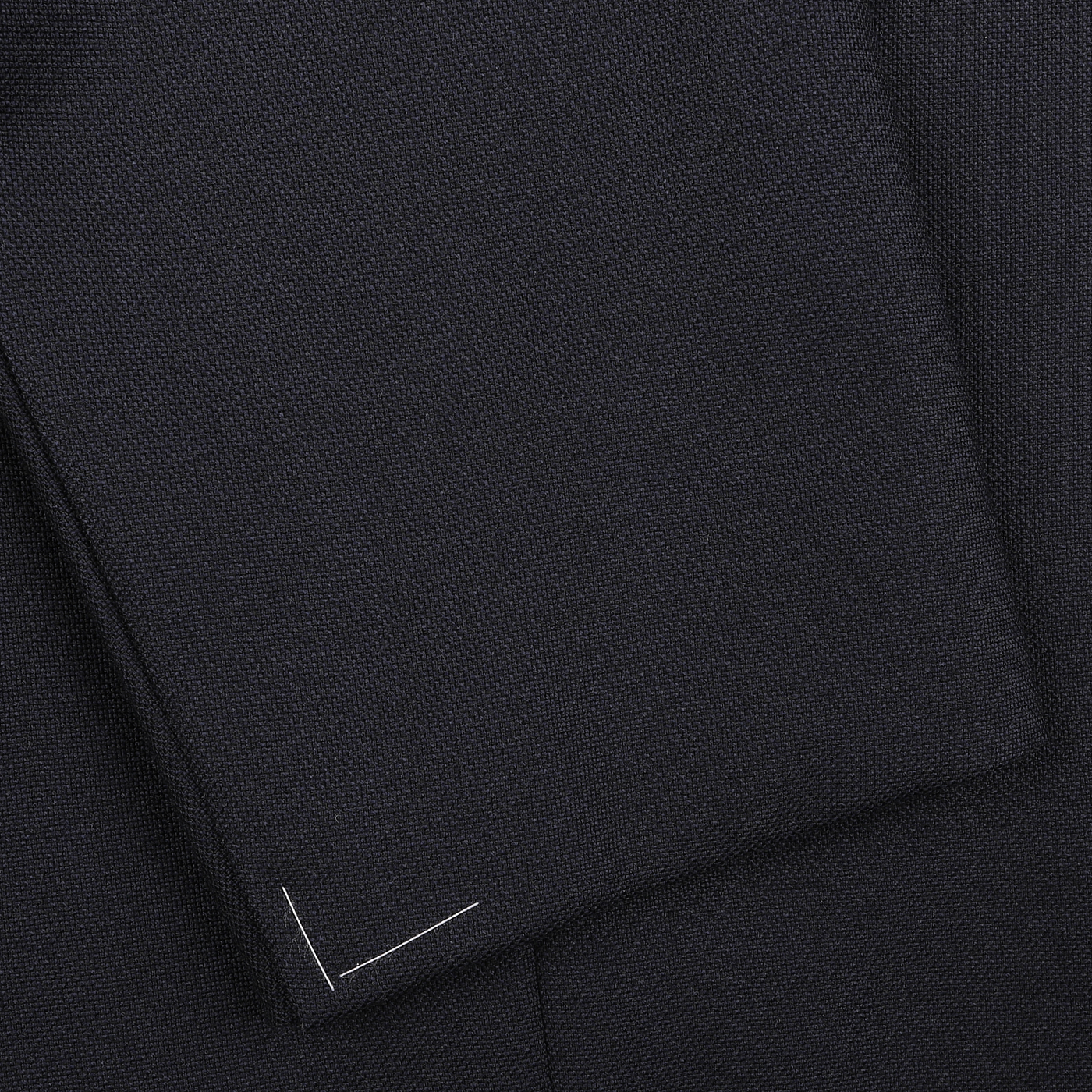 Close-up of navy blue fabric with a subtle textured pattern reminiscent of high-twist wool, featuring a small white stitching detail from the Ring Jacket's Calm Twist Wool Suit collection.