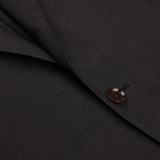 Close-up of a Ring Jacket Dark Brown High Twist Wool Suit fabric with a detailed view of a stitched button.