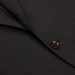 Close-up of a Ring Jacket Dark Brown High Twist Wool Suit fabric with a detailed view of a stitched button.