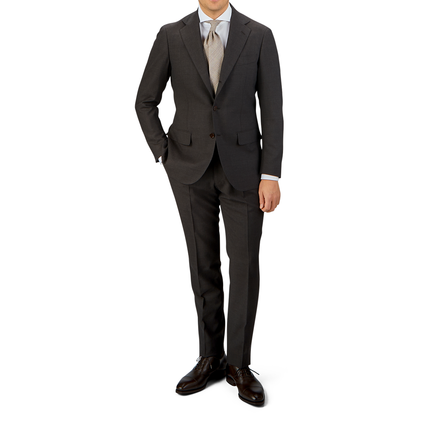 Man in a Ring Jacket tailored Dark Brown High Twist Wool Suit made of wool fresco fabric, with a white shirt and patterned tie, standing with one hand in his pocket, wearing dark brown dress shoes.