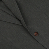 Close-up of a Ring Jacket dark green wool balloon travel blazer fabric with detailed stitching and a brown button.