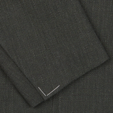 Close-up of a Ring Jacket Dark Green Wool Balloon Travel Blazer fabric with a small white thread stitched in the shape of a "V" on the corner.