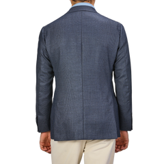 A person is shown from the back, wearing a Denim Blue Wool Balloon Travel Blazer by Ring Jacket in an elegant blazer style with beige pants.