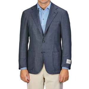 A person wearing the Ring Jacket Denim Blue Wool Balloon Travel Blazer over a light blue shirt and beige pants, with a visible tag on the sleeve, exuding an air of relaxed sophistication.