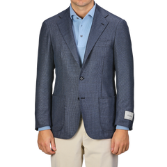 A person wearing the Ring Jacket Denim Blue Wool Balloon Travel Blazer over a light blue shirt and beige pants, with a visible tag on the sleeve, exuding an air of relaxed sophistication.