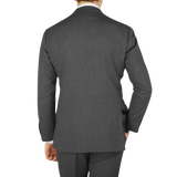 Rear view of a man wearing a Dark Grey High Twist Wool Suit by Ring Jacket, standing against a light gray background.