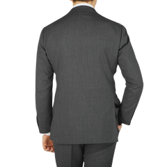 Rear view of a man wearing a Dark Grey High Twist Wool Suit by Ring Jacket, standing against a light gray background.