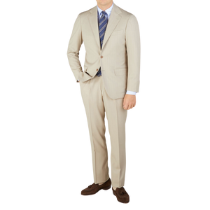 A man is posing in a Light Beige Herringbone Wool Suit by Ring Jacket.