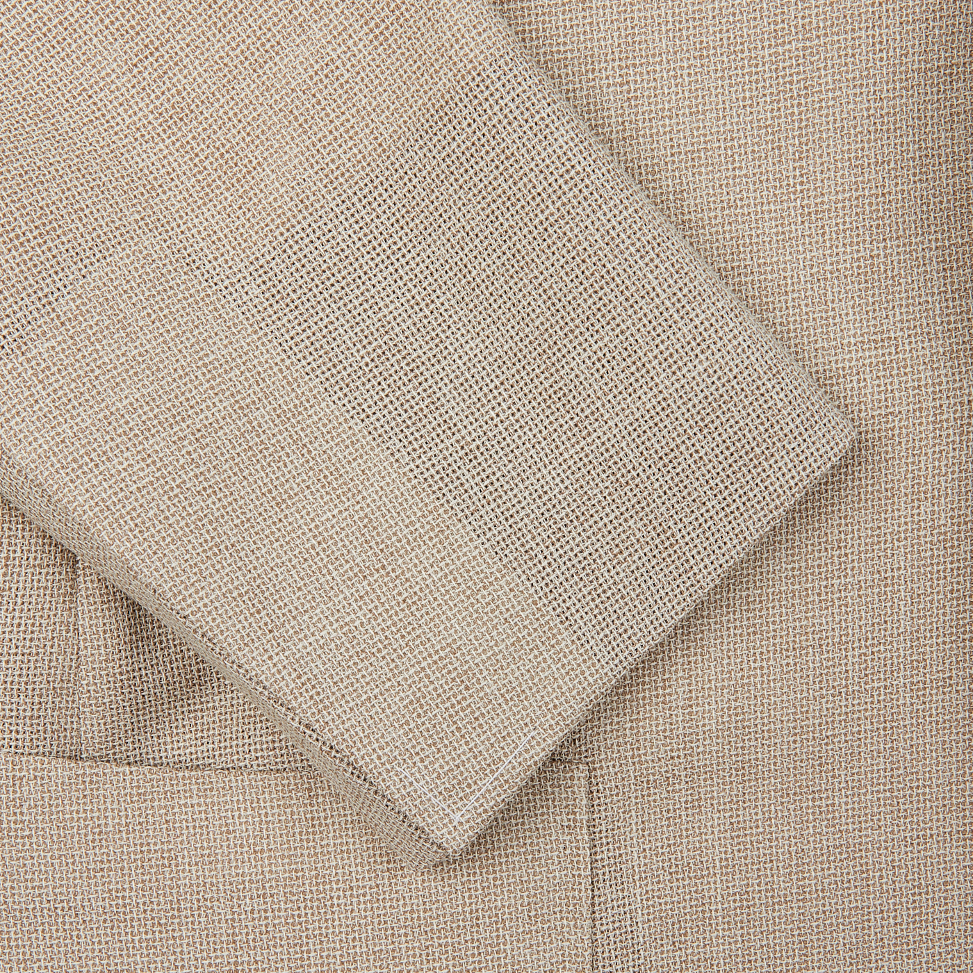 Close-up view of a light beige Ring Jacket Wool Balloon Travel Blazer texture with a folded corner, highlighting the detailed weave pattern.