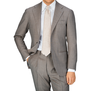 A man in a Ring Jacket Mid Grey High-Twist Wool Suit with his hand in his pocket.