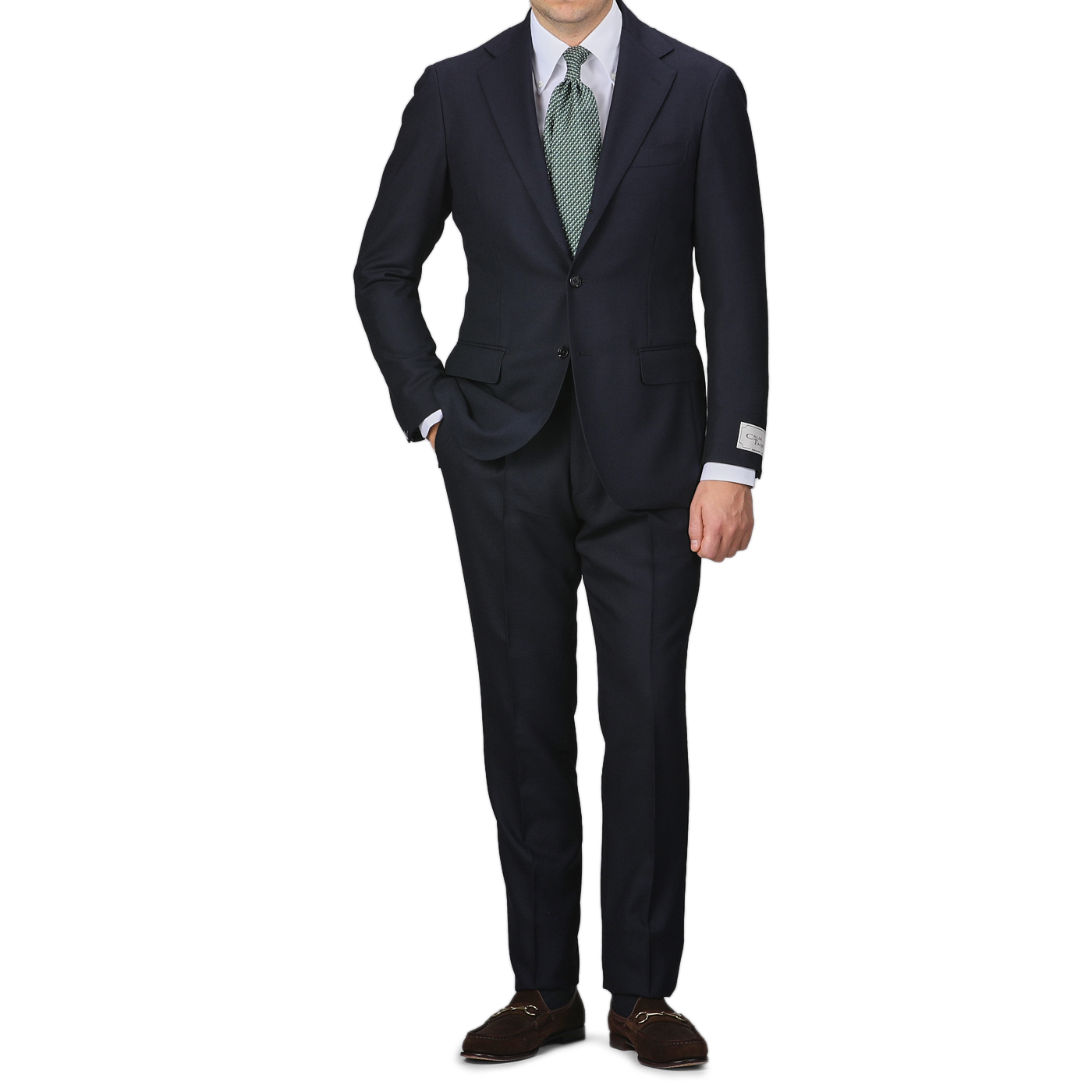 A person in the Navy Blue Calm Twist Wool Suit by Ring Jacket, complemented with a green tie and brown shoes, stands against a plain background, highlighting the elegance of full canvas construction in high-twist wool fabric.