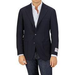 Man wearing a Ring Jacket Navy Blue Wool Balloon Travel Blazer over a white shirt paired with jeans, standing against a gray background.