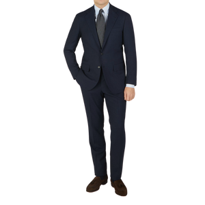 A man wearing a Ring Jacket Navy High Twist Wool Suit and tie made from fresco fabric.