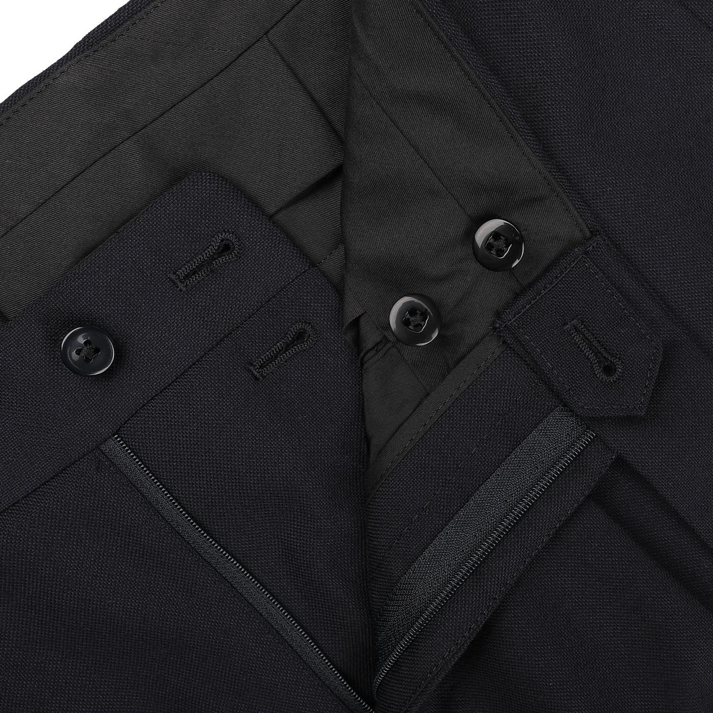 Close-up of the Navy Blue Calm Twist Wool Suit by Ring Jacket, showcasing the waistband, buttons, and zipper detail on the pair of dark-colored dress pants crafted from high-twist wool fabric.