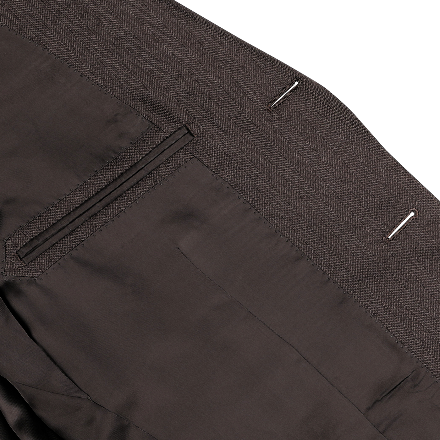 A close-up view of neatly stitched dress pants from the Brown Herringbone Calm Twist Wool Suit by Ring Jacket, showcasing the refined details of the back pocket and belt loops, crafted from high-twist wool fabric.