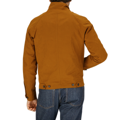 Man wearing a Sealup Tobacco Brown Cotton Harrington Waxed Jacket and blue jeans from a rear view.