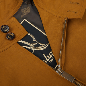 Close-up of a tobacco brown Cotton Harrington Waxed Jacket by Sealup with a partially unzipped zipper and a designer label visible.