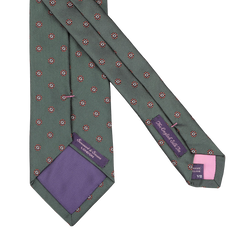 The Bottle Green Printed Medallion Silk Tie from Seaward & Stearn showcases a handmade design in a light green shade, adorned with delicate red and white floral patterns. This exquisite piece features a purple lining and visible brand labels, seamlessly blending elegance with exceptional craftsmanship.