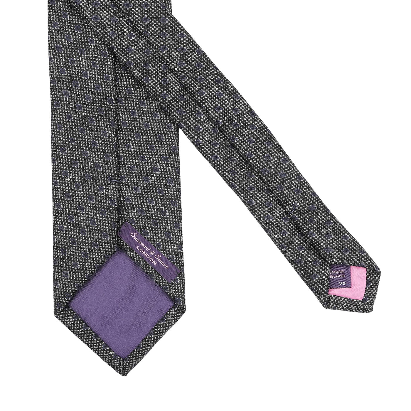 The Grey Blue Dot Wool Tie by Seaward & Stearn showcases a gray pattern with a purple lining, crafted from pure wool and featuring tags with brand details. Handmade in England, it combines elegance with a touch of distinction.