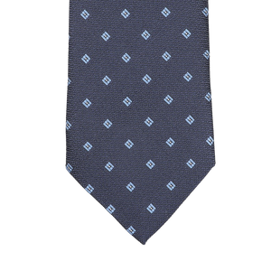 The Seaward & Stearn Navy Blue Diamond Woven Silk Tie is a handmade silk masterpiece, showcasing a navy blue color with an intricate pattern of small light blue square motifs.