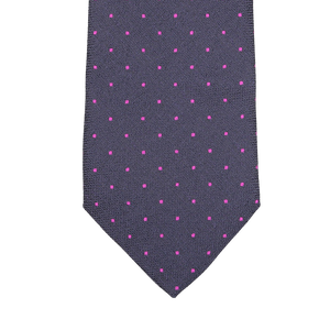 Close-up of a silk tie by Seaward & Stearn in a rich navy blue hue, featuring tiny pink dots woven into an elegant pattern.