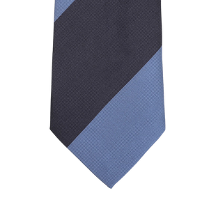 A close-up of the Seaward & Stearn Navy Blue Striped Silk Tie highlights a diagonal design with navy blue and dark gray sections against a light gray background, exemplifying the elegance of this handmade silk necktie.