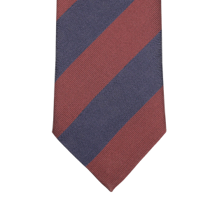 A detailed view of the Rust Blue Striped Silk Tie by Seaward & Stearn, featuring diagonal maroon and navy blue stripes set against a light gray background, expertly handcrafted in England.