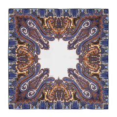 The Cortina Blue Silk Pocket Square by Sera Fine Silk showcases an intricate paisley pattern in shades of blue, orange, and gold, with a central white area and exquisite hand-rolled edges.