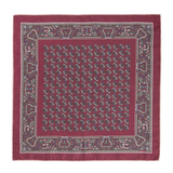 A luxurious pocket square named the Rose Montepulciano by Sera Fine Silk, crafted from exquisite Como silk, featuring an intricate paisley pattern with a detailed border and repeating smaller designs in the center. The edges are meticulously hand-rolled to complete this maroon masterpiece.