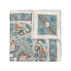 The Vernazza Cream Silk Pocket Square by Sera Fine Silk is expertly folded and showcases an intricate paisley design in shades of blue, green, and orange on an ivory background, complete with hand-rolled edges.