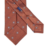 A Silvio Fiorello Orange Herringbone Woven Silk Tie with an orange and blue pattern.