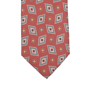 The Brick Red Diamond Printed Silk Lined Tie by Stefano Cau features a sophisticated geometric pattern of overlapping squares and circles in gray and orange, intricately woven into luxurious Italian Como silk. The rich brick red hue enhances the elegance of this exquisite accessory.