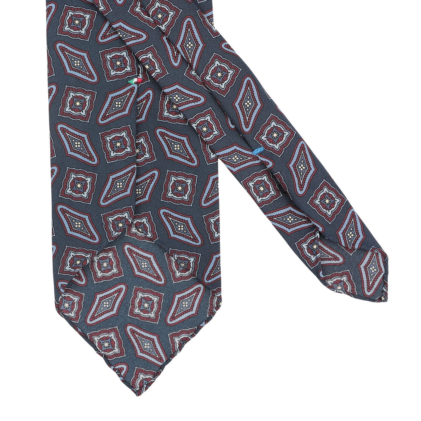 A dark blue kilim-printed silk unlined tie from Stefano Cau showcases a geometric red, blue, and white design, reflecting the elegance of Italian craftsmanship.