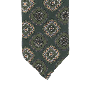 Stefano Cau's Green Medallion Printed Silk Unlined Tie is meticulously crafted from the finest Italian Como silk and showcases a repeating pattern of ornate circular designs in beige, blue, and orange tones.