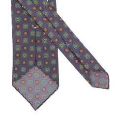 The Stefano Cau Purple Flower Printed Silk Unlined Tie is an exquisite accessory crafted from luxurious Italian Como silk, featuring a vibrant floral and geometric pattern in teal, yellow, and orange set against a plain white background—perfect for elevating any sophisticated ensemble.