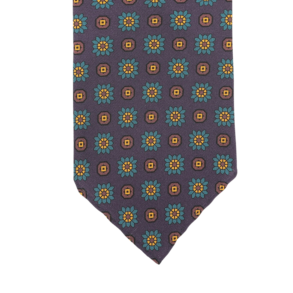 Close-up of a Stefano Cau tie meticulously crafted from luxurious Italian Como silk, showcasing a pattern of purple flowers with yellow squares against a dark background.