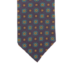 Close-up of a Stefano Cau tie meticulously crafted from luxurious Italian Como silk, showcasing a pattern of purple flowers with yellow squares against a dark background.