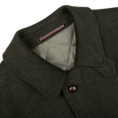 Steinbock's Dark Green Wool Alpaca Loden Coat exudes a refined style, featuring a quilted interior, pointed collar, and a single visible leather football button on the front.