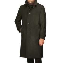 A man wearing the Dark Green Wool Alpaca Loden Coat by Steinbock, crafted from a premium wool-alpaca blend, showcases leather football buttons and practical side pockets.