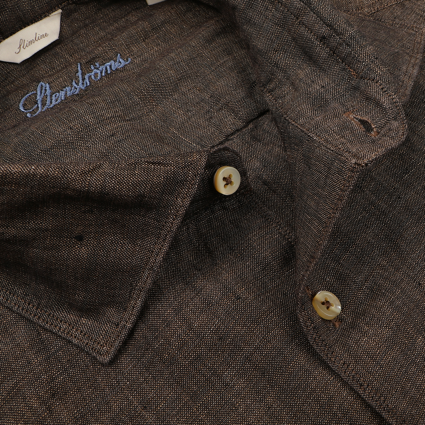 Close-up of a Dark Brown Linen Cutaway Slimline Shirt by Stenströms, featuring an embroidered label on the inner yoke and two front buttons—a true summer essential.